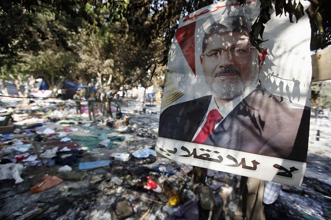 A poster of deposed president Mohamed Mursi which reads, "No to the coup", is near debris of a protest camp outside the burnt Rabaa Adawiya mosque, in Cairo